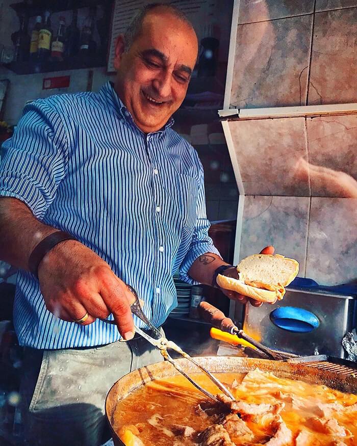 cocinero preparando un bocadillo de bacalao en una taberna en Lisboa