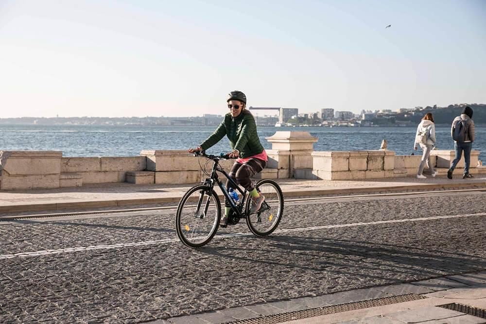 Mujer montando en bici a lo largo del Río Tajo en Lisboa