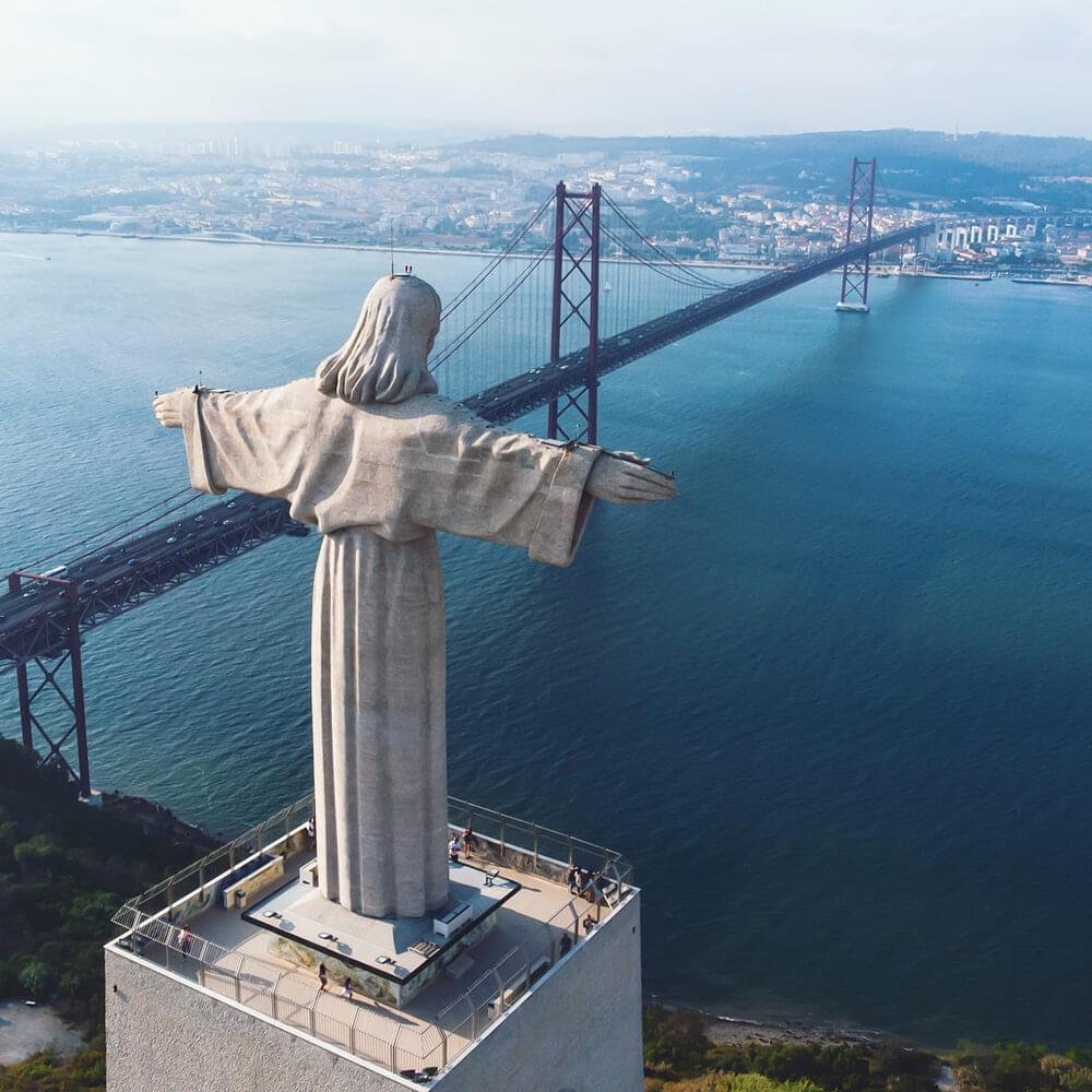 Cristo-Rei monument with the 25th of April bridge and the Tagus river in the background